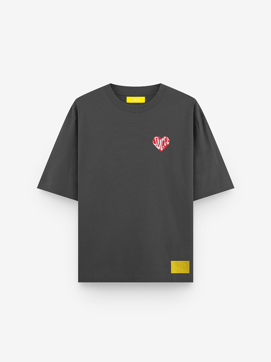 Black streetwear t-shirt with small red heart graphic on chest and yellow tag at hem