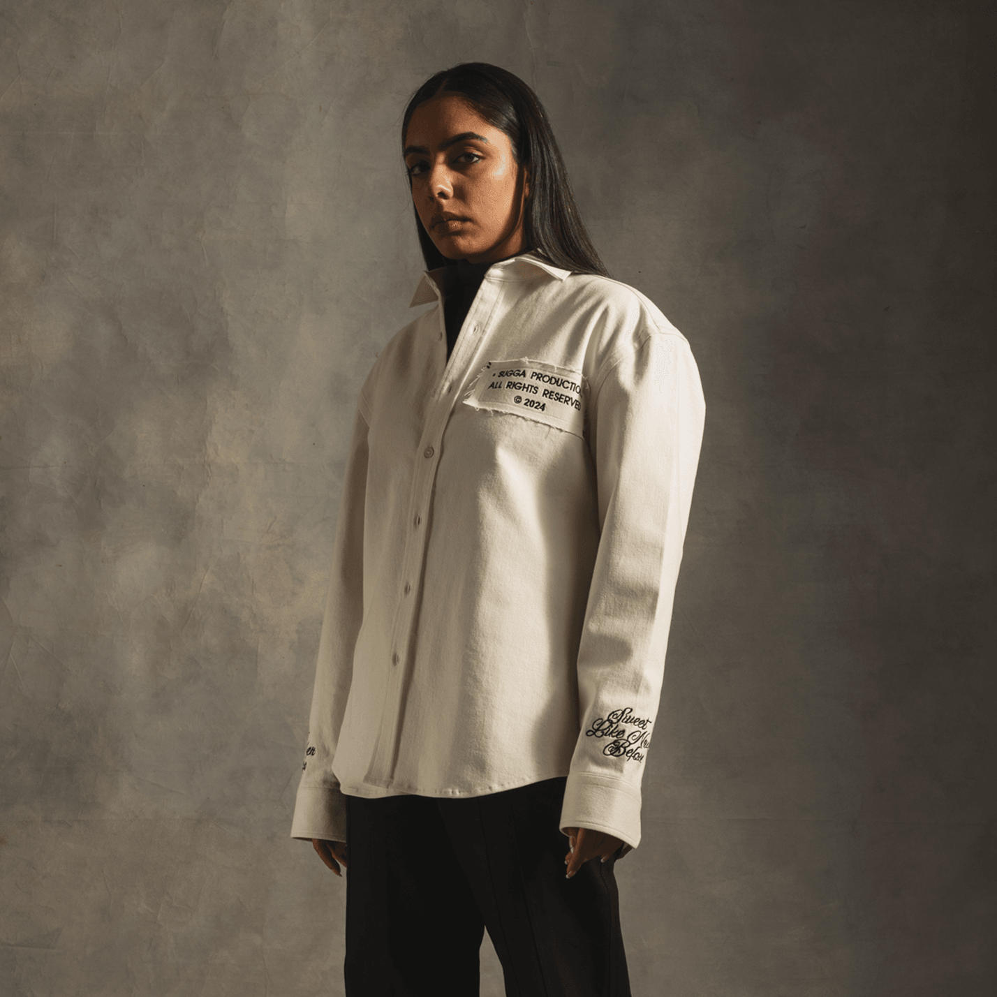 Woman in white streetwear button-up shirt with black text details, neutral background