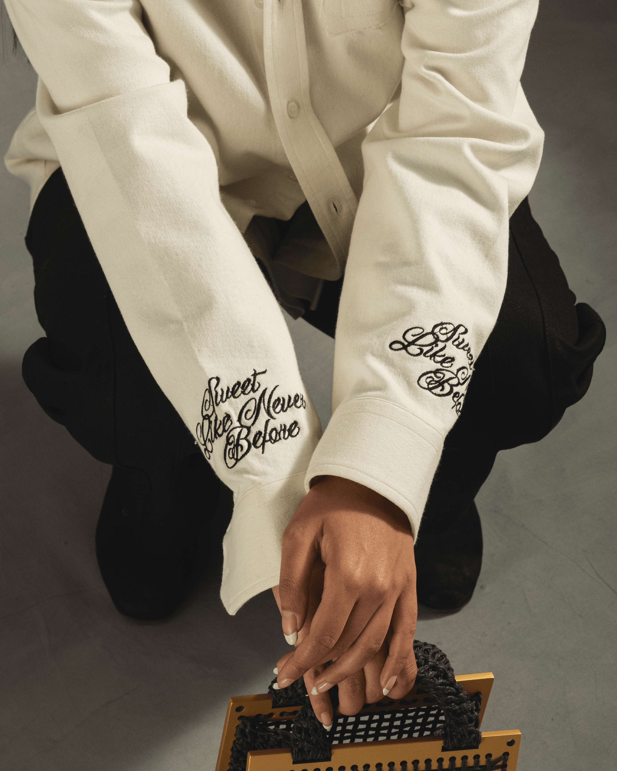 Close-up of embroidered streetwear shirt sleeves with 'Sweet Like Never Before' lettering
