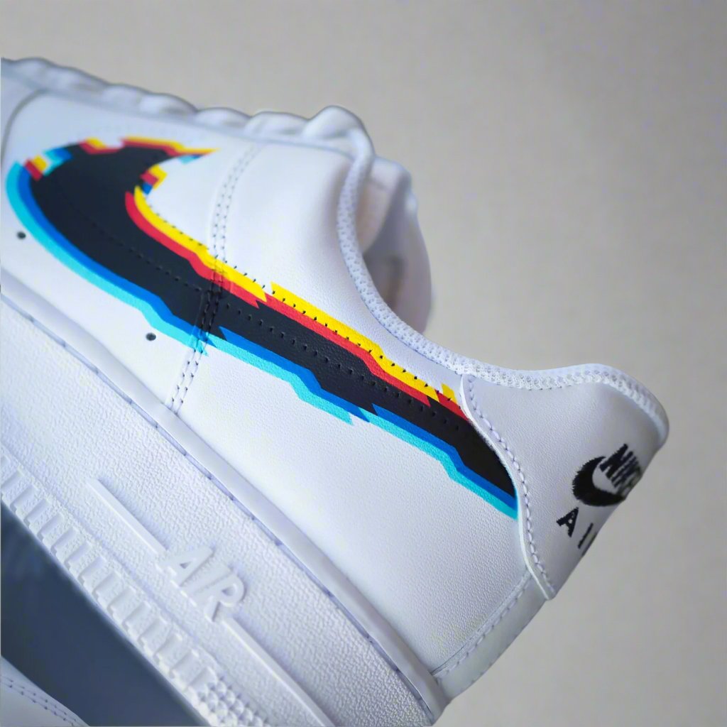 White Nike Air sneaker with multicolor swoosh in blue, yellow, red, and black accent.