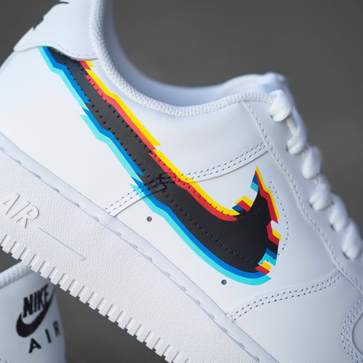 White Nike Air Force 1 sneaker with multicolor outlined swoosh, streetwear shoe closeup