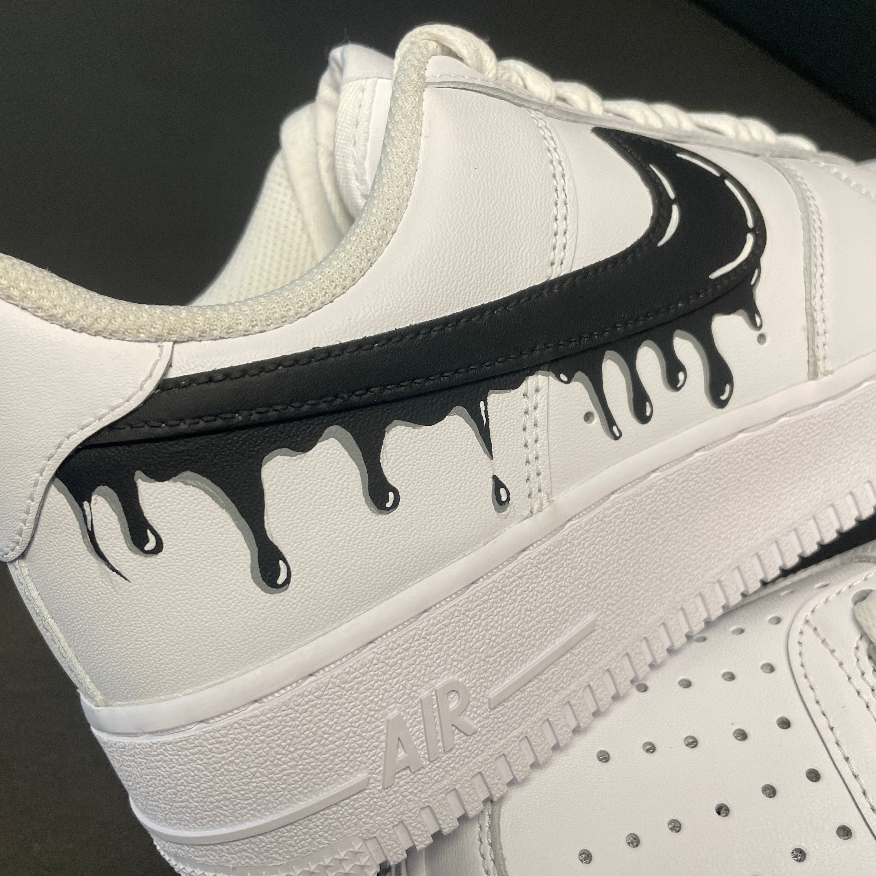 White streetwear sneaker with black drip swoosh design and textured sole, side view