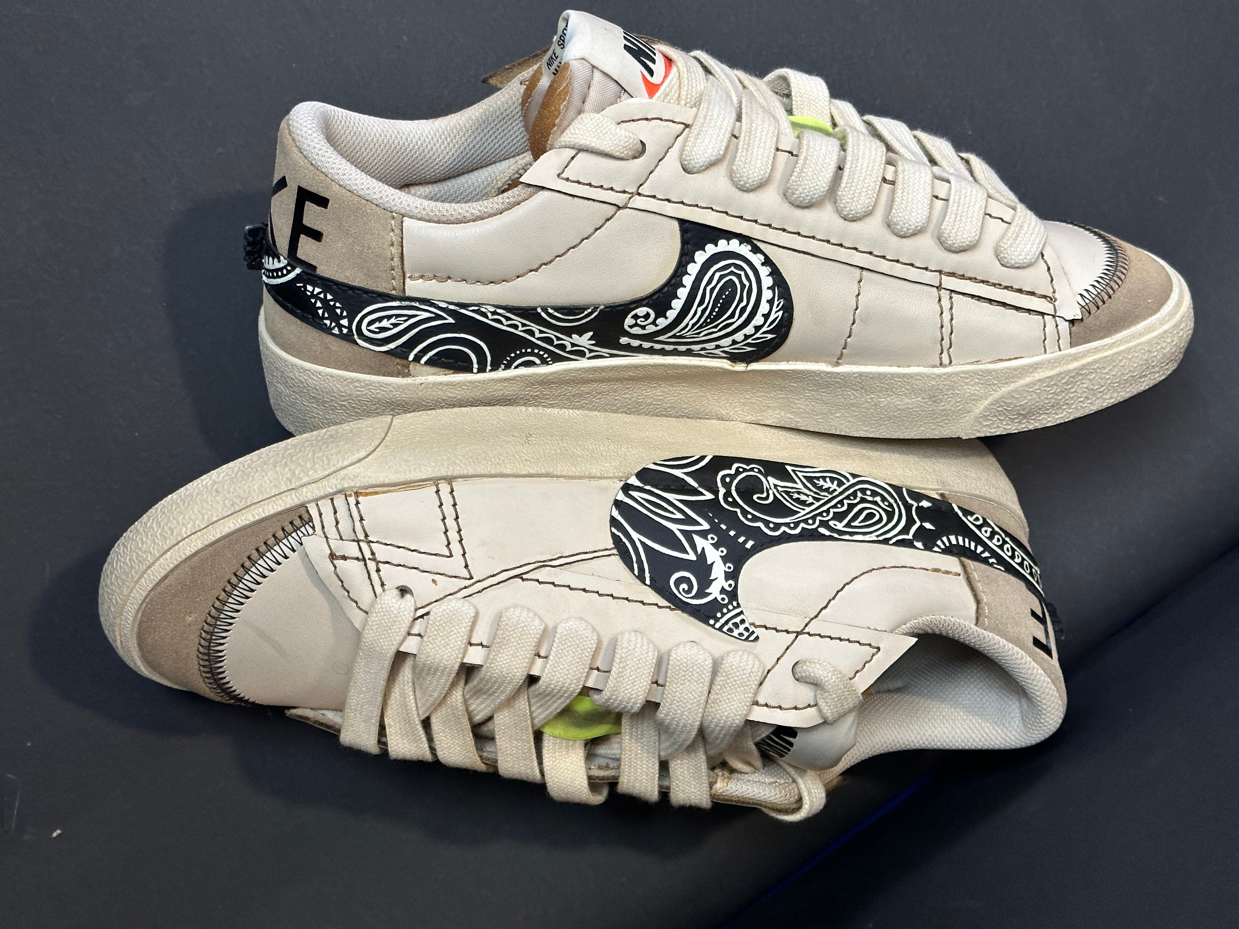 White low-top streetwear sneakers with paisley black swoosh and suede detailing
