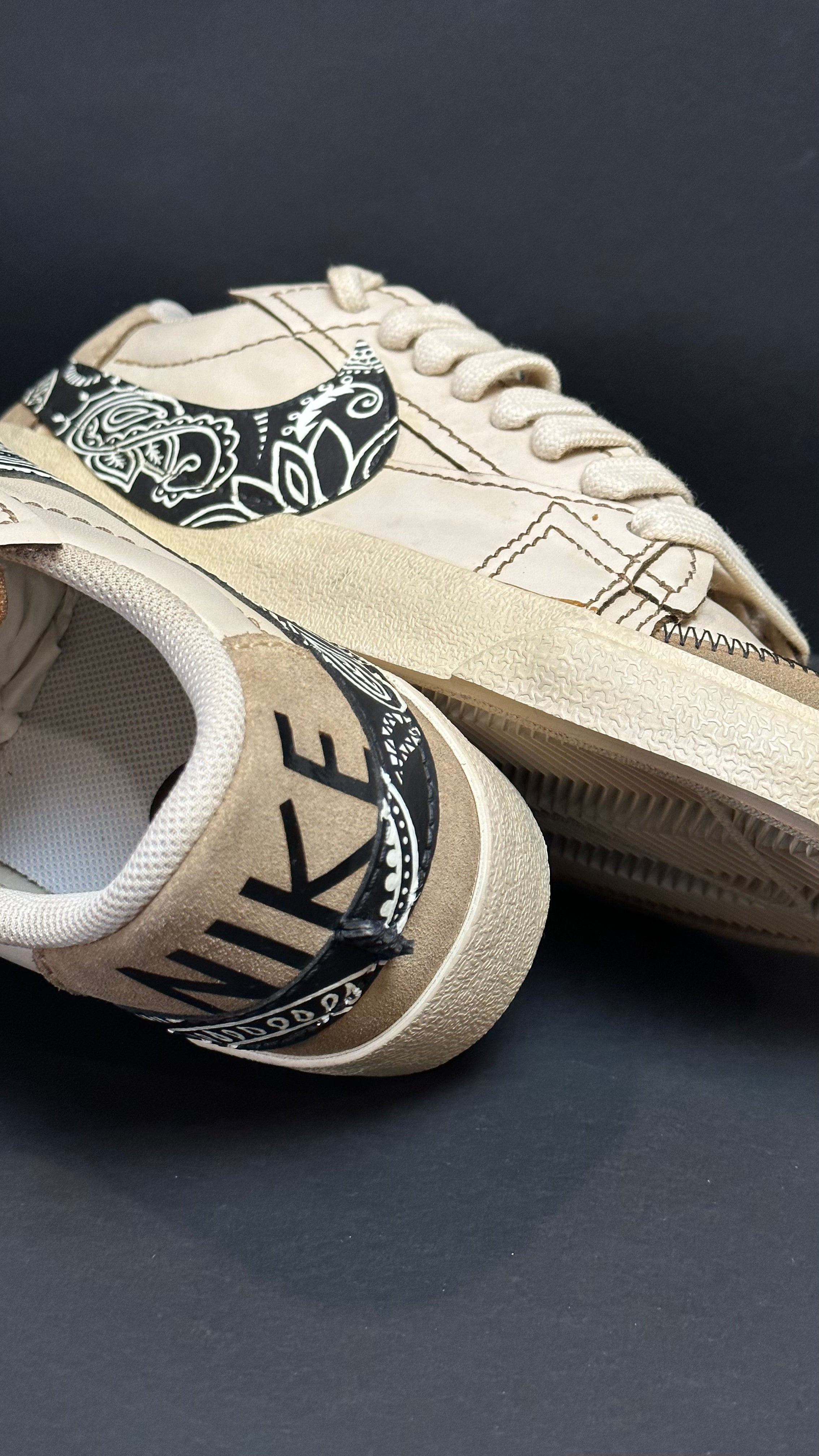 Beige streetwear sneakers with black paisley swoosh and NIKE branding detail