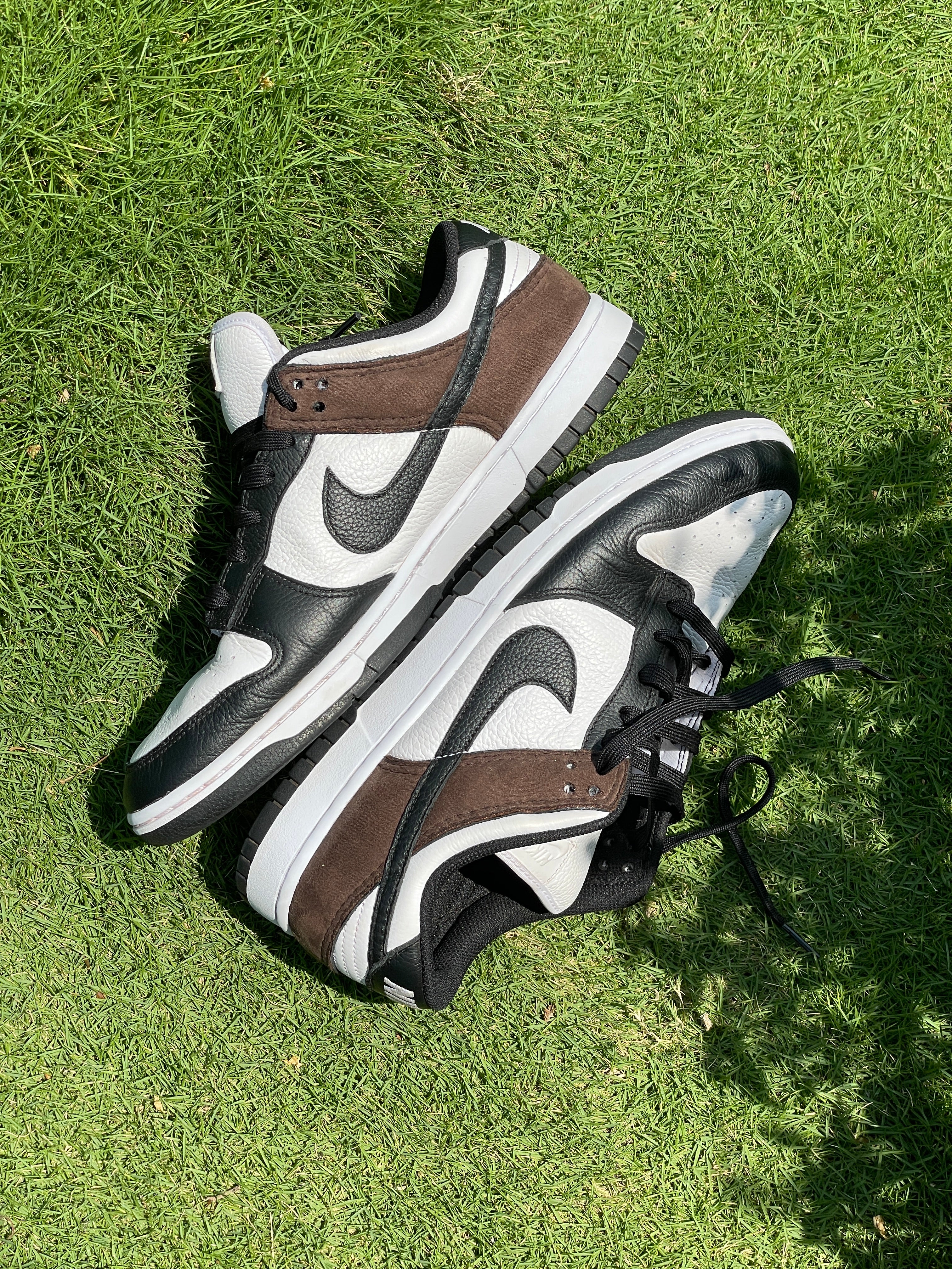 Black, white, and brown low-top sneakers with leather and suede panels on green grass