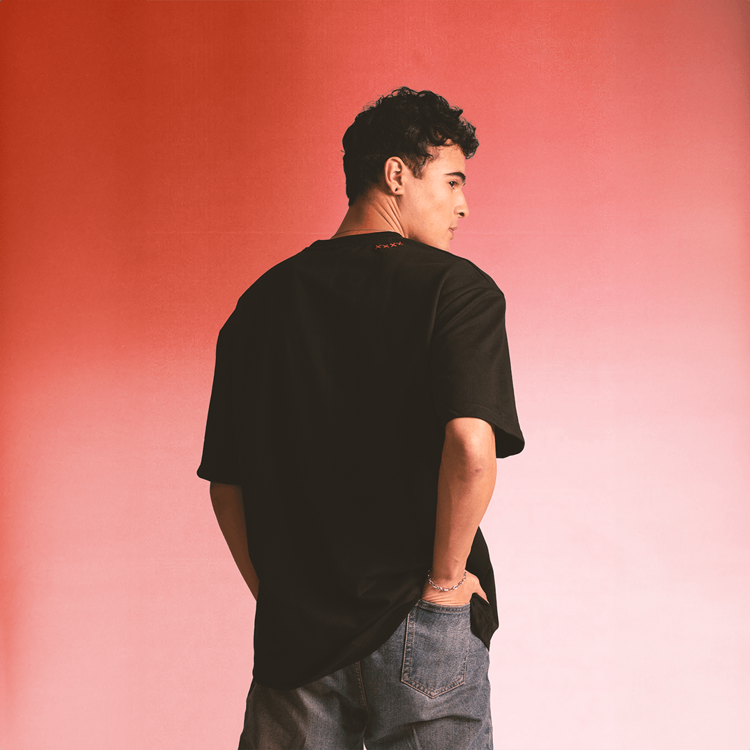 Man in casual streetwear with a black t-shirt and denim jeans against a pink gradient background