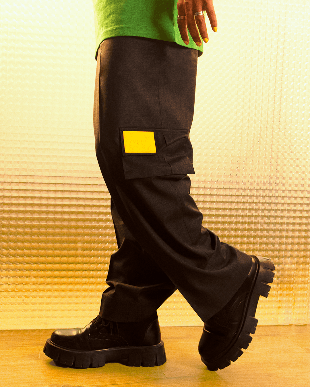Black cargo pants with yellow patch and chunky black boots, styled in streetwear fashion.