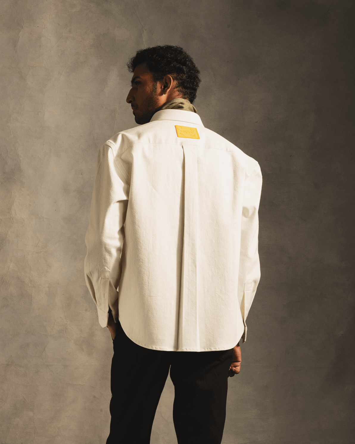 Back view of man wearing white long sleeve streetwear shirt with yellow patch accent