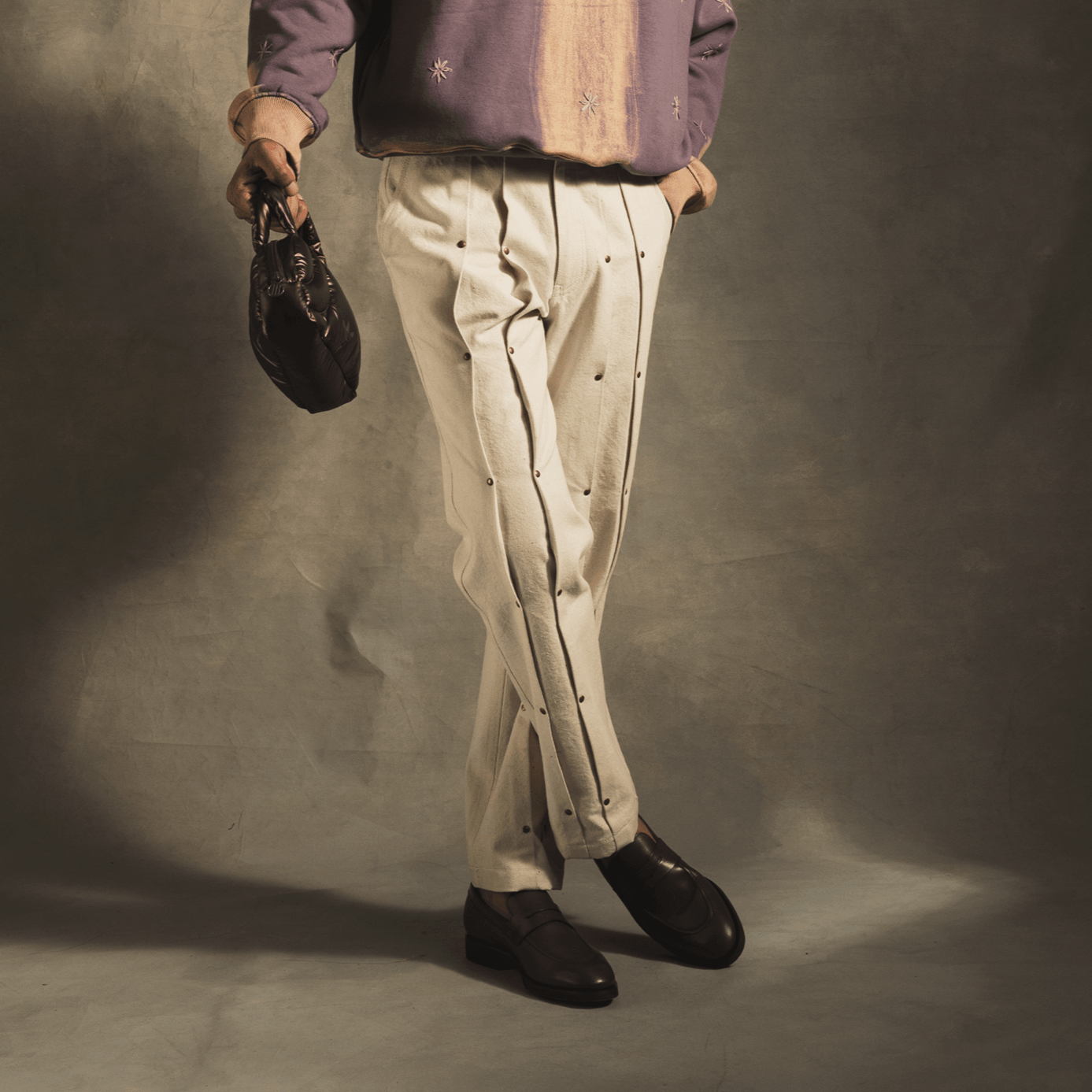 Streetwear outfit with a purple sweatshirt, cream pants with studs, and black loafers