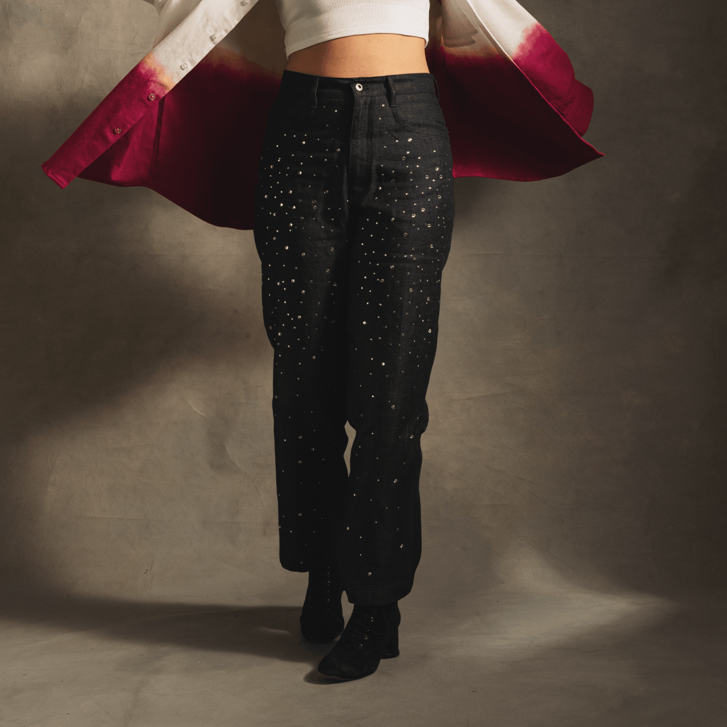 Black star-studded jeans with straight leg fit, worn with cropped top and pink jacket.