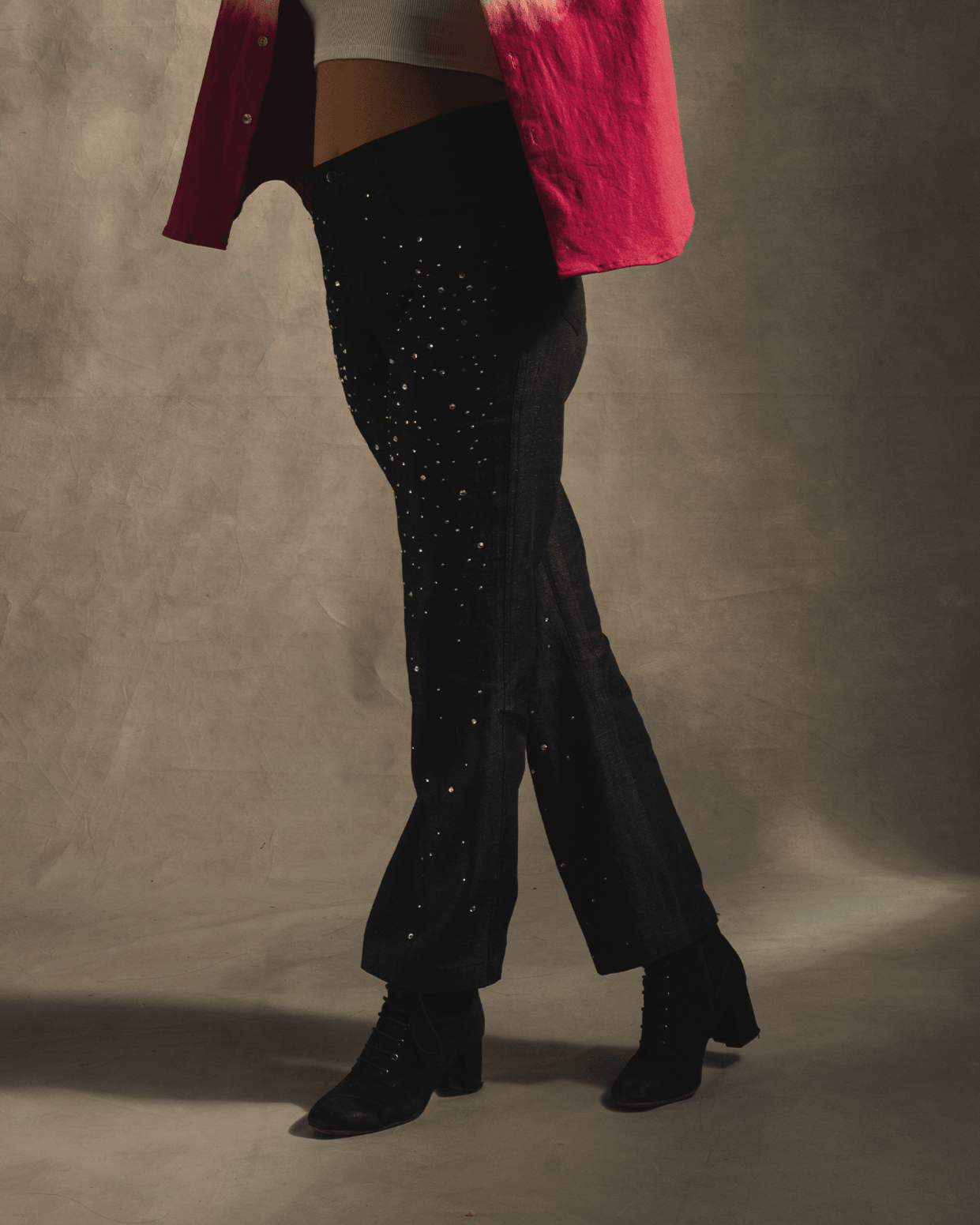 Woman in star-studded black jeans, heeled boots, pink shirt, white top, studio setting