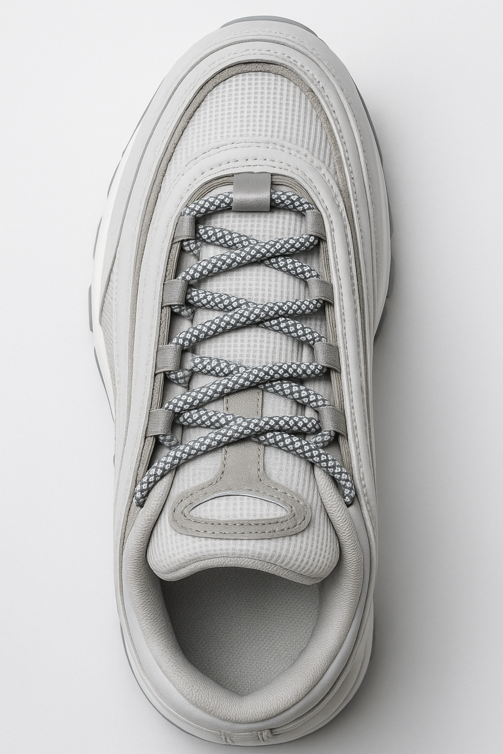 White sneaker with white reflective laces on a light gray background
