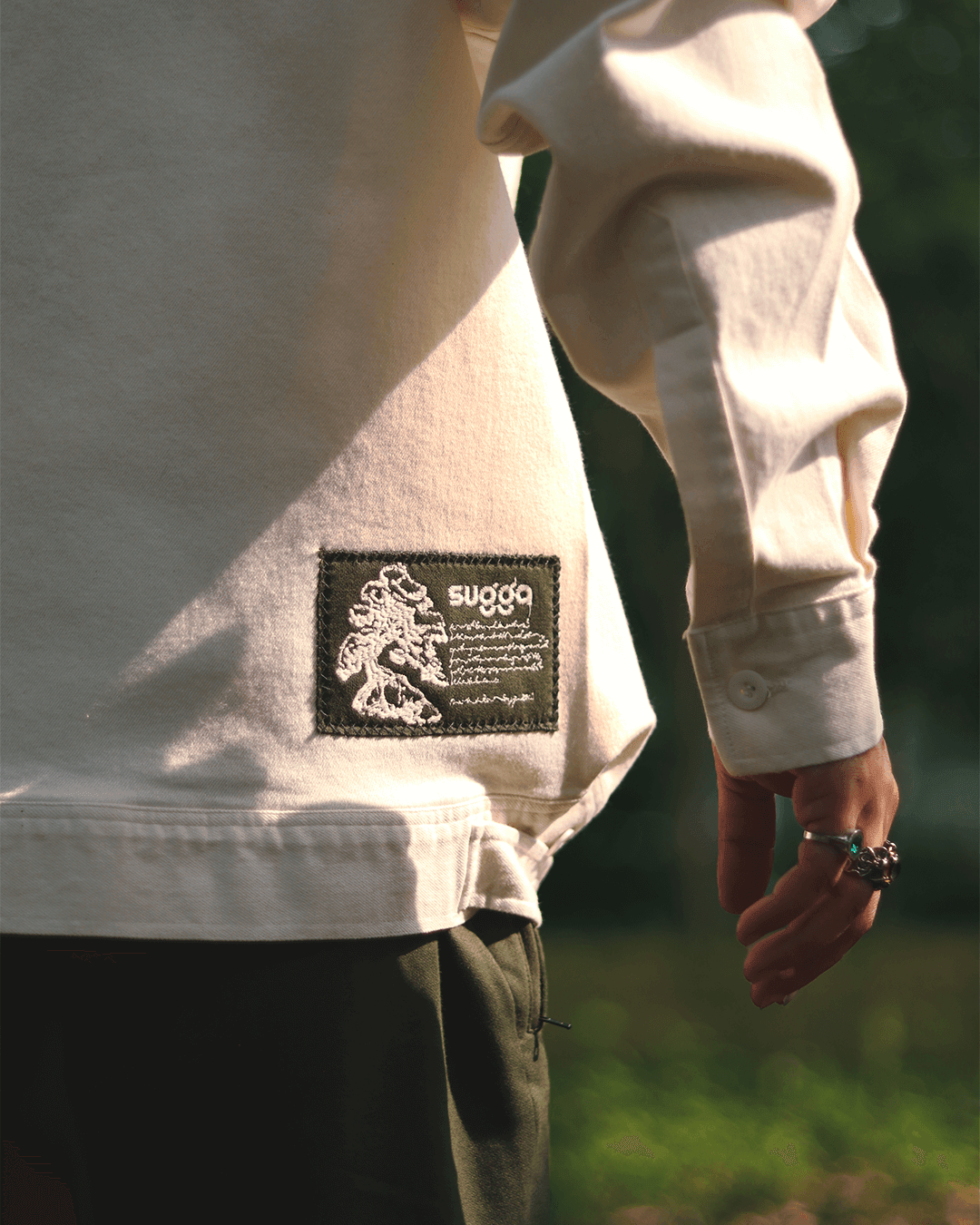 Close-up of a white streetwear hoodie with an embroidered black patch and graphic design detail.