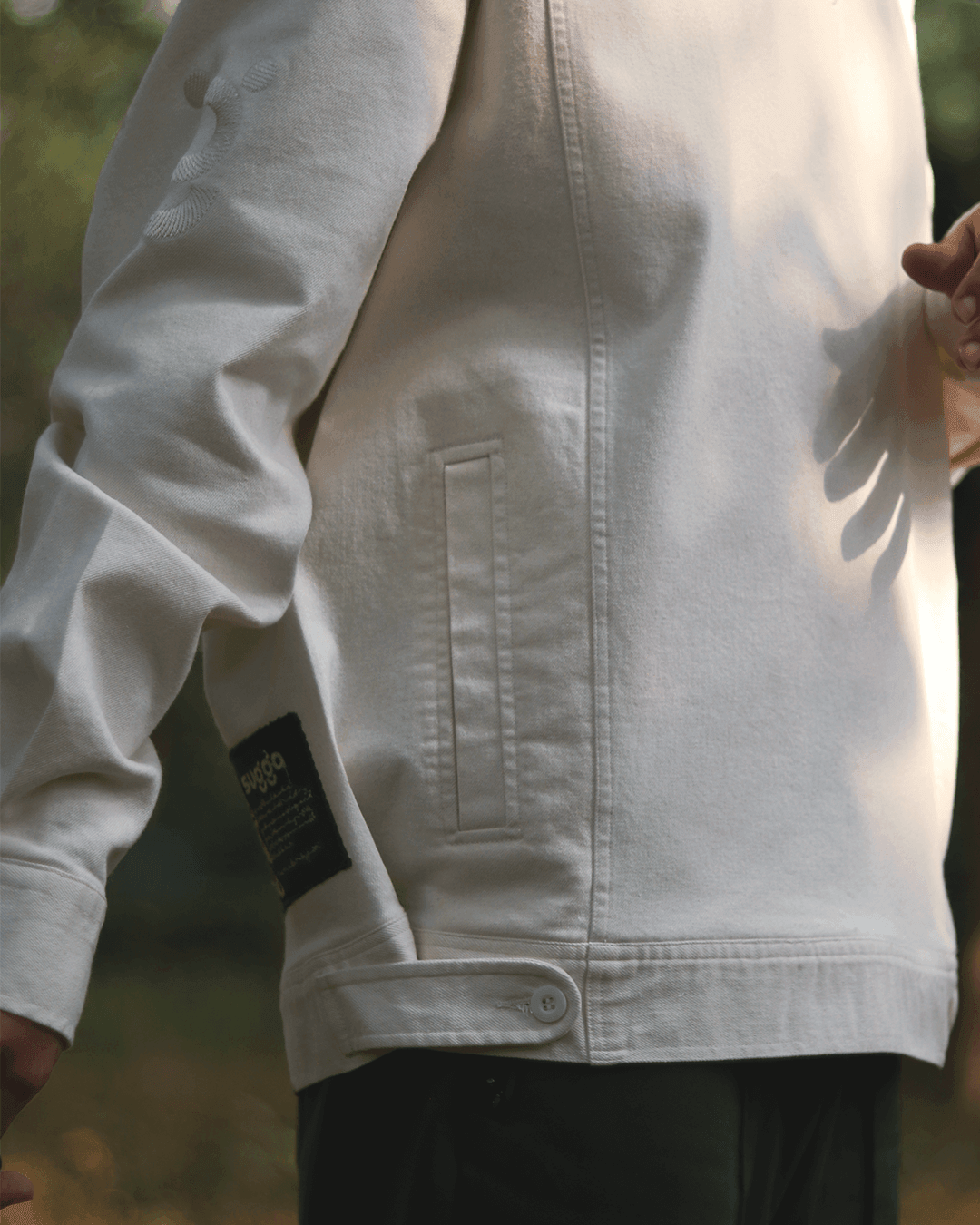 White streetwear jacket with side pocket, patch detail, and subtle sleeve embroidery