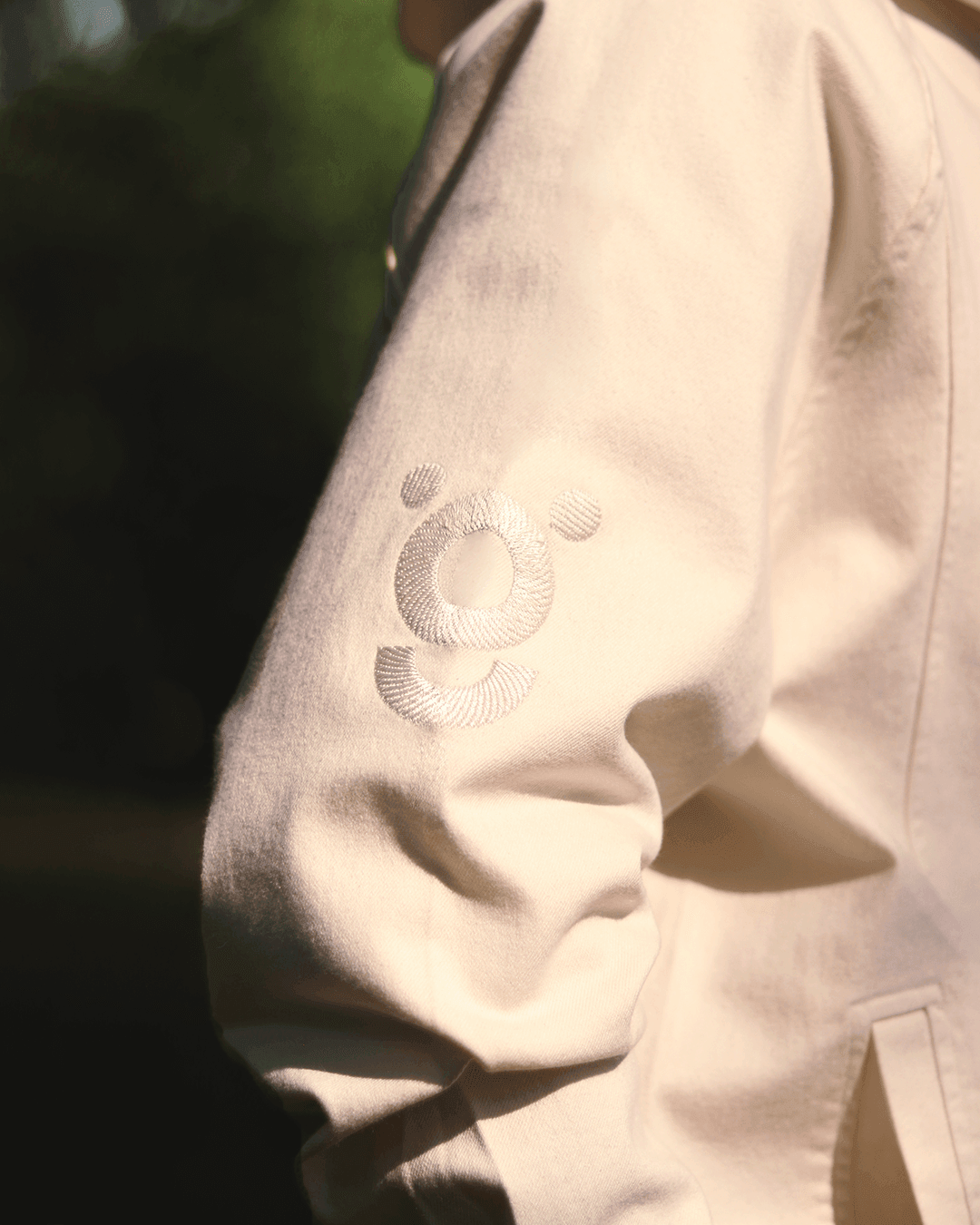 White hoodie sleeve with embroidered logo, streetwear fashion, close-up view