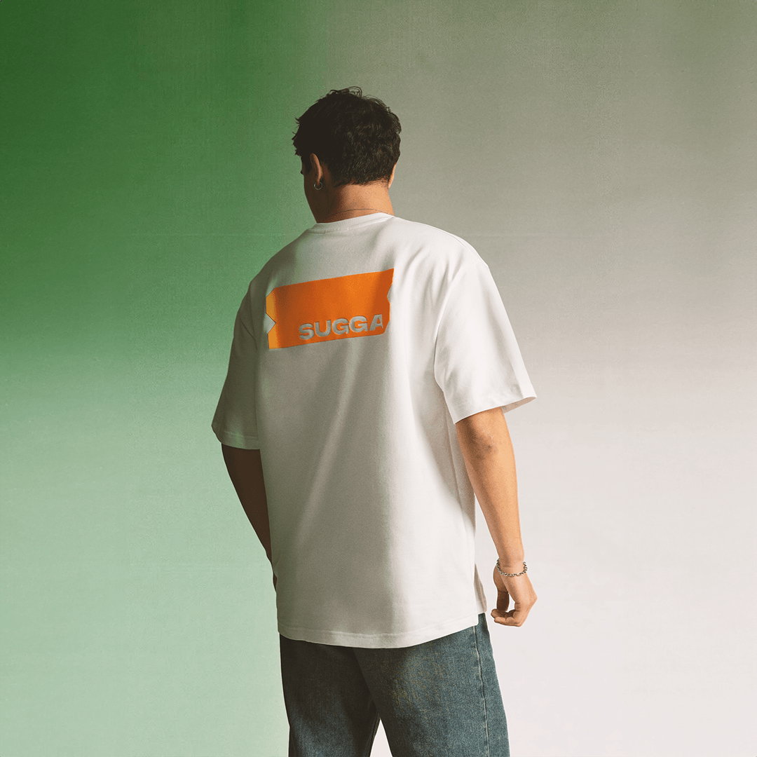 Man wearing a white streetwear t-shirt with orange SUGGA graphic on the back, casual style