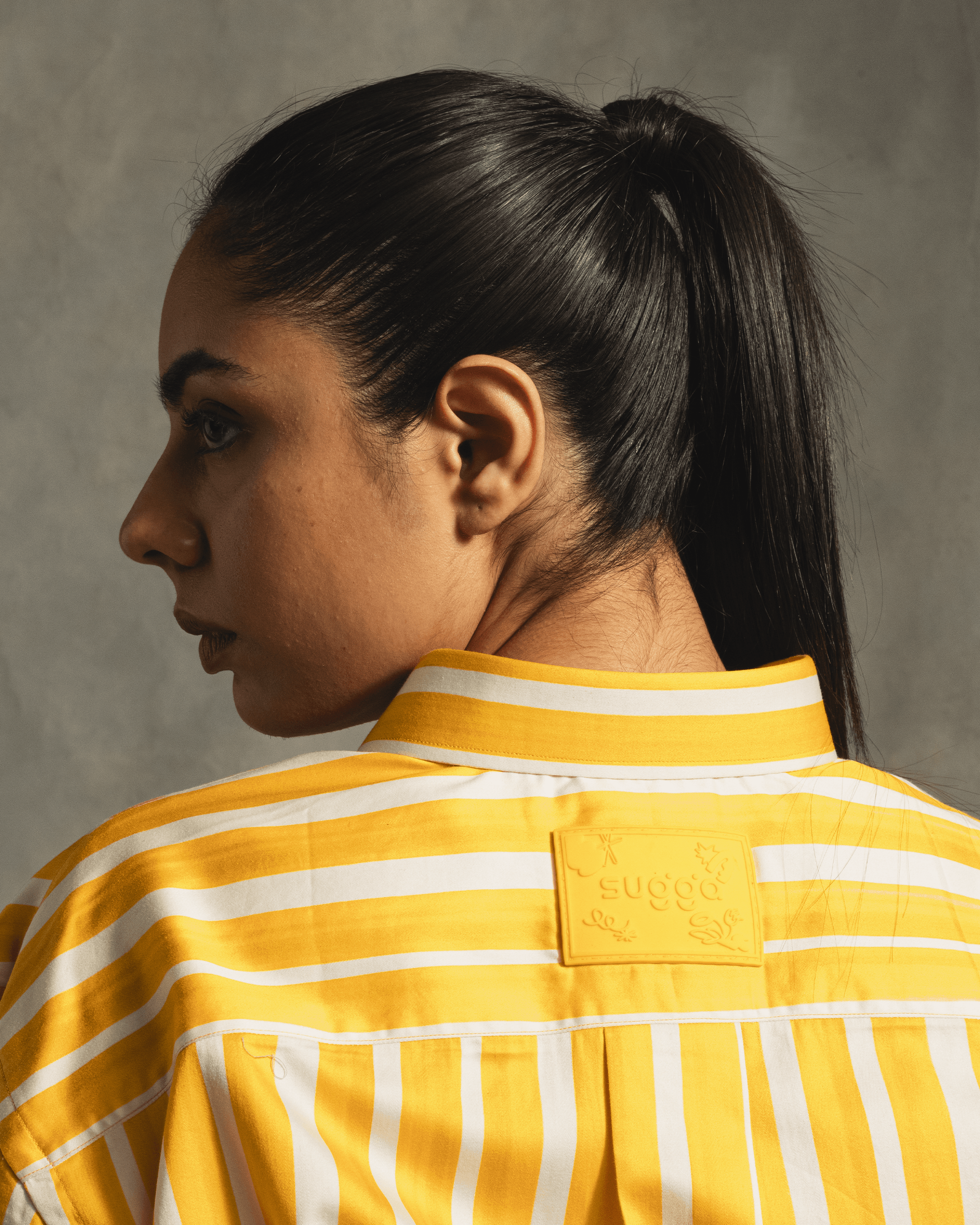 Woman models yellow and white striped streetwear shirt with patch detail on back