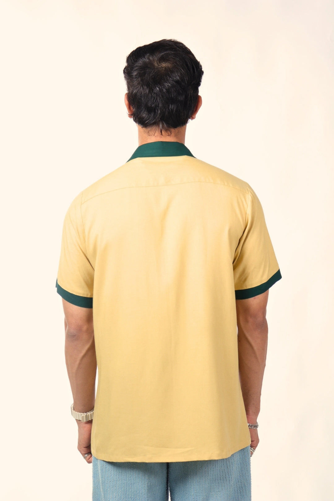 Back view of man wearing short sleeve yellow shirt with green collar and cuffs, casual style