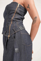 Close-up of woman wearing dark blue denim outfit with zipper and brown stitching, jellyfish and dragon tattoos on arm