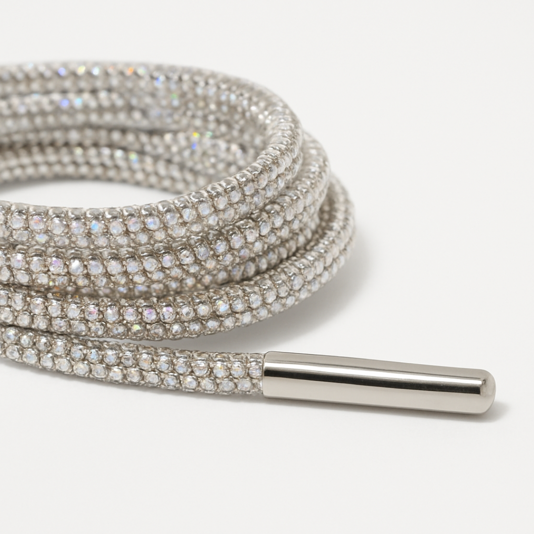 Silver shoe laces with rhinestone detailing on a white background