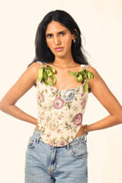 Woman wearing a floral corset top with green ribbon straps and blue jeans, streetwear fashion