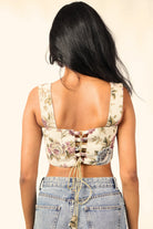 Woman in floral lace-up crop top and high-waisted blue jeans, back view, street fashion style