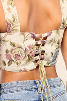 Close-up of a floral tapestry lace-up crop top back paired with blue denim jeans.