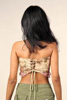 Woman wearing a floral lace-up crop top and olive green cargo pants, back view
