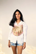 Woman wearing floral corset over white shirt and denim shorts, streetwear fashion