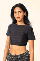 Woman wearing a black crop top and distressed black denim jeans, streetwear fashion