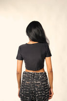 Woman wearing a black crop top and distressed black denim pants, back view, streetwear style