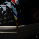 Close-up of a black sneaker with  Gradient  colorful laces on a dark background