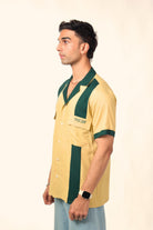 Man wearing short-sleeve yellow and green bowling shirt with 'cerise' text, side view