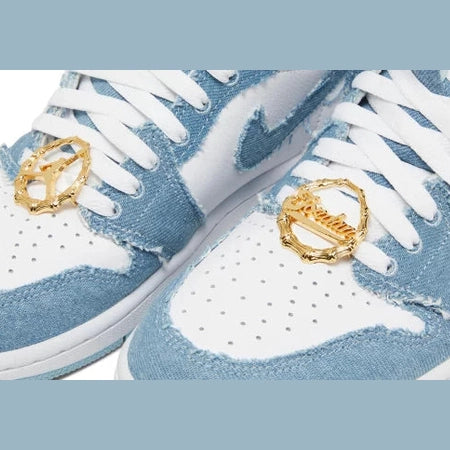 Close-up of light blue denim sneakers with white laces and gold lace charms