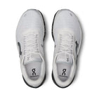 Pair of white On Cloudmonster running shoes with black soles, top view, mesh uppers, visible branding