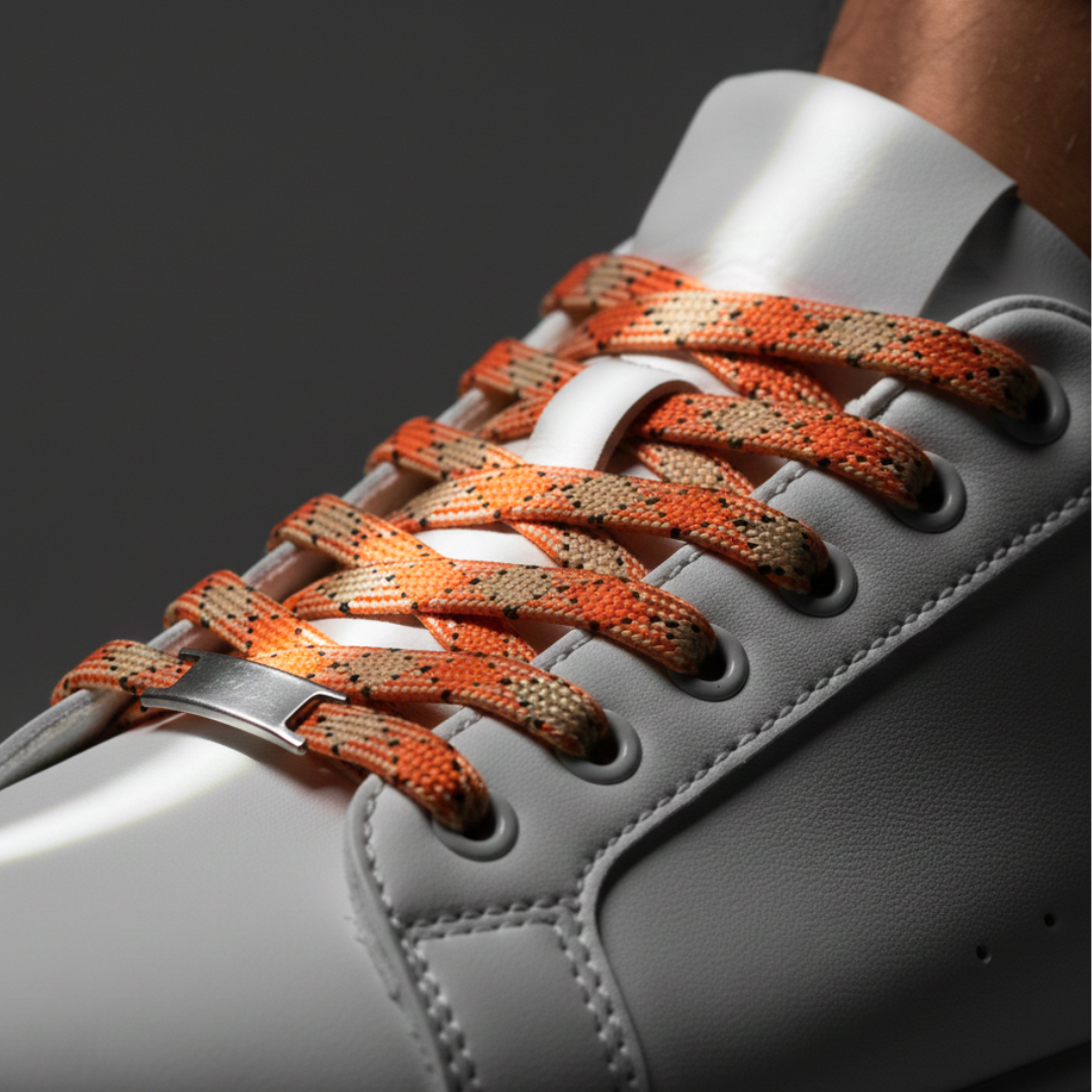 white sneaker with orange and brown braided laces on a dark background