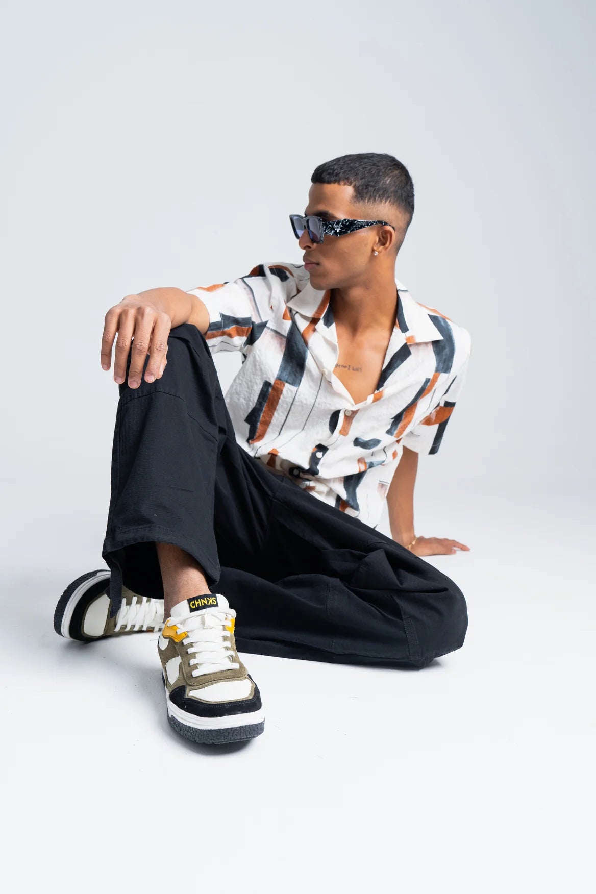 Model wearing Taxi CHNKS sneakers with white shirt and black trousers – men’s yellow and green sneakers for streetwear style