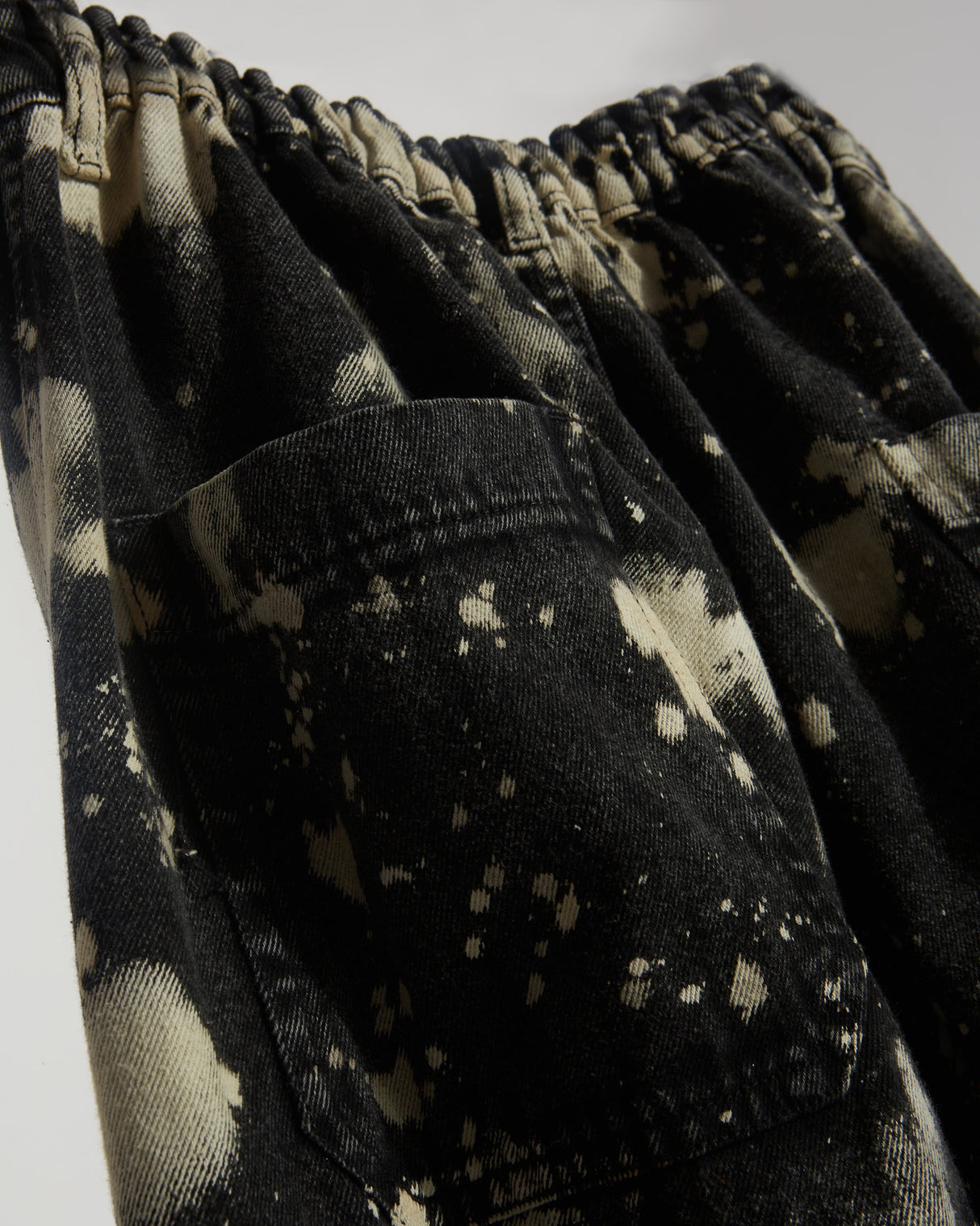 Dark wash black denim cargo pants with Hypo bleach effect.