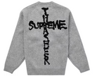 Gray knit sweater with black graphic cross and bold streetwear-style lettering on back