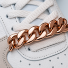 Rose gold chain bracelet on a white sneaker