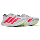 Light grey running sneakers with bold coral stripes and neon yellow sole accents