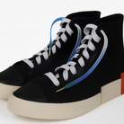 Black high-top sneakers with white laces and blue accents on a light gray background