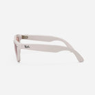 Side view of white designer sunglasses with pink lenses and bold frame