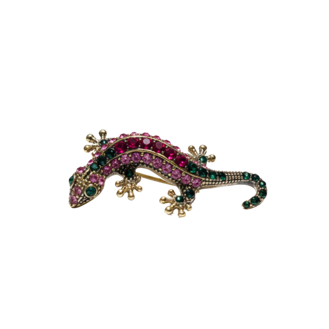 Gold-tone gecko sneaker charm with pink and green crystal detailing on black background